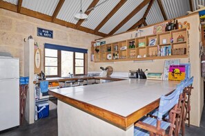 Een keuken met een groot eiland, houten balken, een raam en een bord waarop staat 'RUE DE BAYE'.