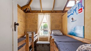 A compact room with bunk beds, a window with curtains, and a wall with a surfing-themed mural.