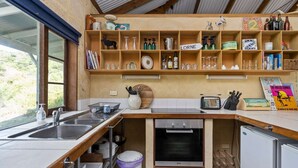 A compact kitchen with a wooden countertop, a built-in oven, and a wine rack. - Kangaroo Cottage – Beachside Escape in Dawesville (Dawesville)