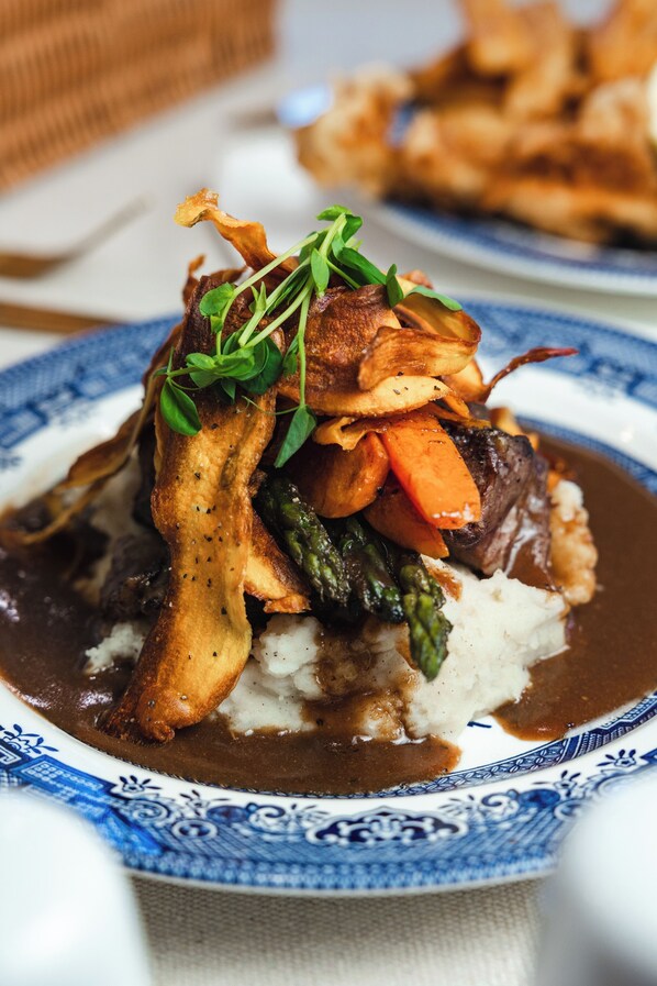 Une assiette de nourriture comprenant un steak de bœuf, des légumes et de la purée de pommes de terre.
