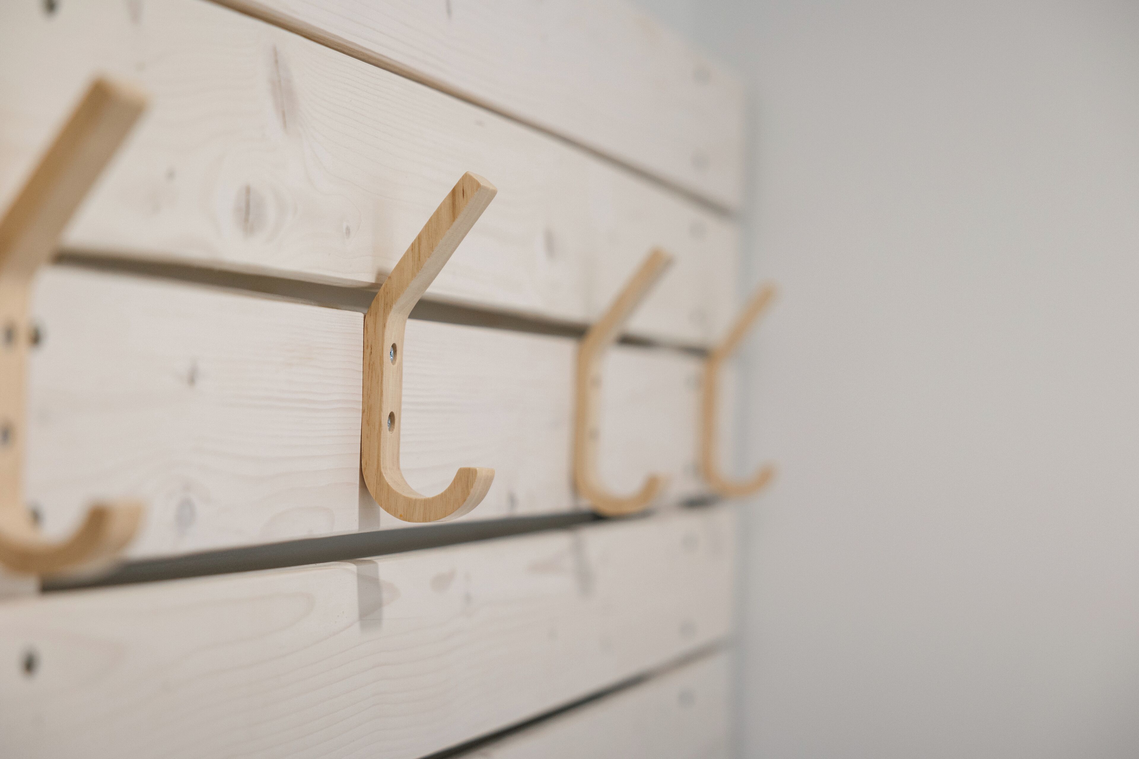 A wooden wall with three wooden hooks.