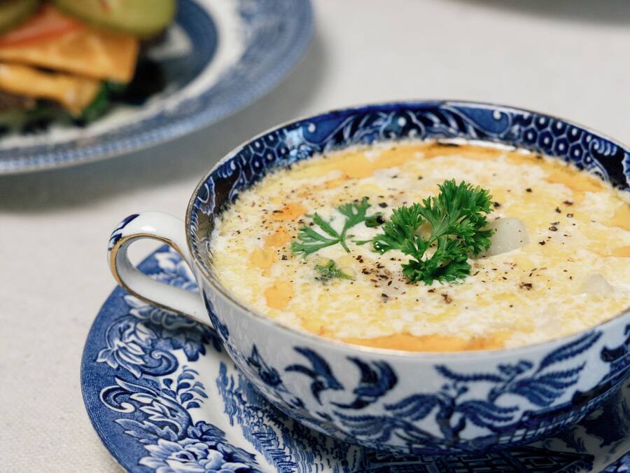 A bowl of soup on a blue and white patterned plate.
