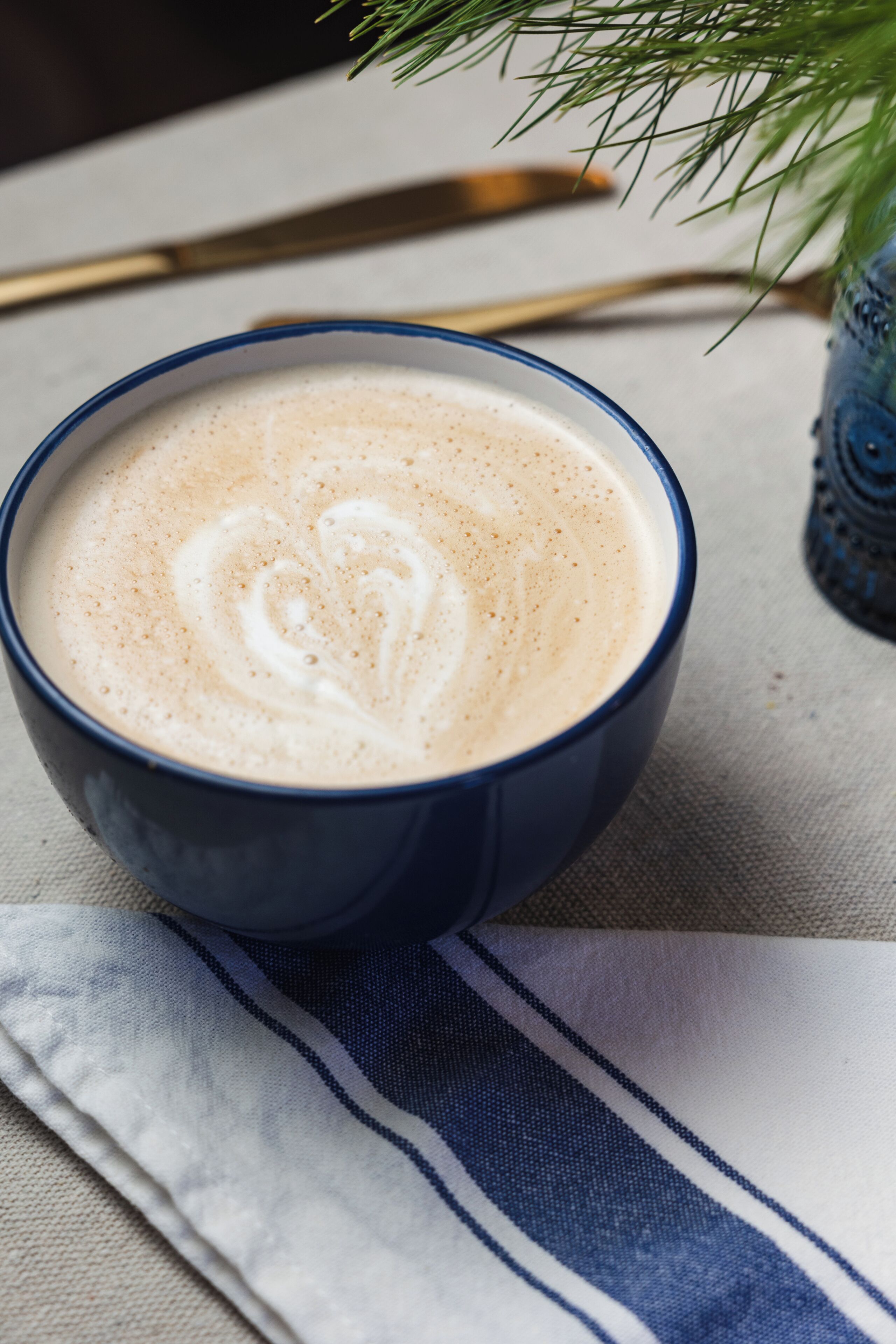 A cup of coffee with latte art on a textured surface.