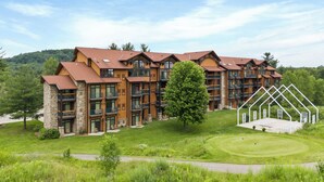 A multi-story hotel with a stone facade, multiple balconies, and a well-maintained lawn. - Tee Time Terrace - Near Attractions / Waterpark (Wisconsin Dells)