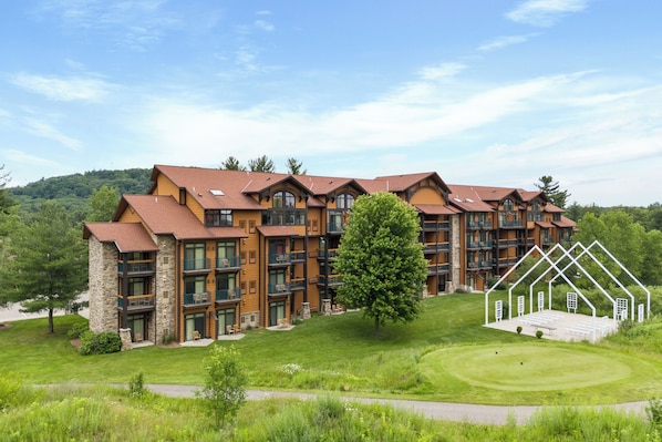 A multi-story hotel with a stone facade, multiple balconies, and a well-maintained lawn. - Tee Time Terrace - Near Attractions | Freshly Remodeled (Wisconsin Dells)