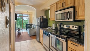 A kitchen with wooden cabinets, stainless steel appliances, and a view to a balcony. - Tee Time Terrace - Near Attractions / Waterpark (Wisconsin Dells)