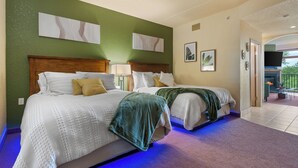 A hotel room with two beds, a green accent wall, artwork, and a view of the outdoors. - Tee Time Terrace - Near Attractions | Freshly Remodeled (Wisconsin Dells)