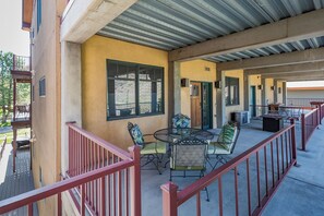 A covered outdoor patio with a dining area, including a table and chairs, and a view of the surrounding area.