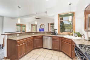 A modern kitchen with a large island, stainless steel appliances, and a view of the outdoors.