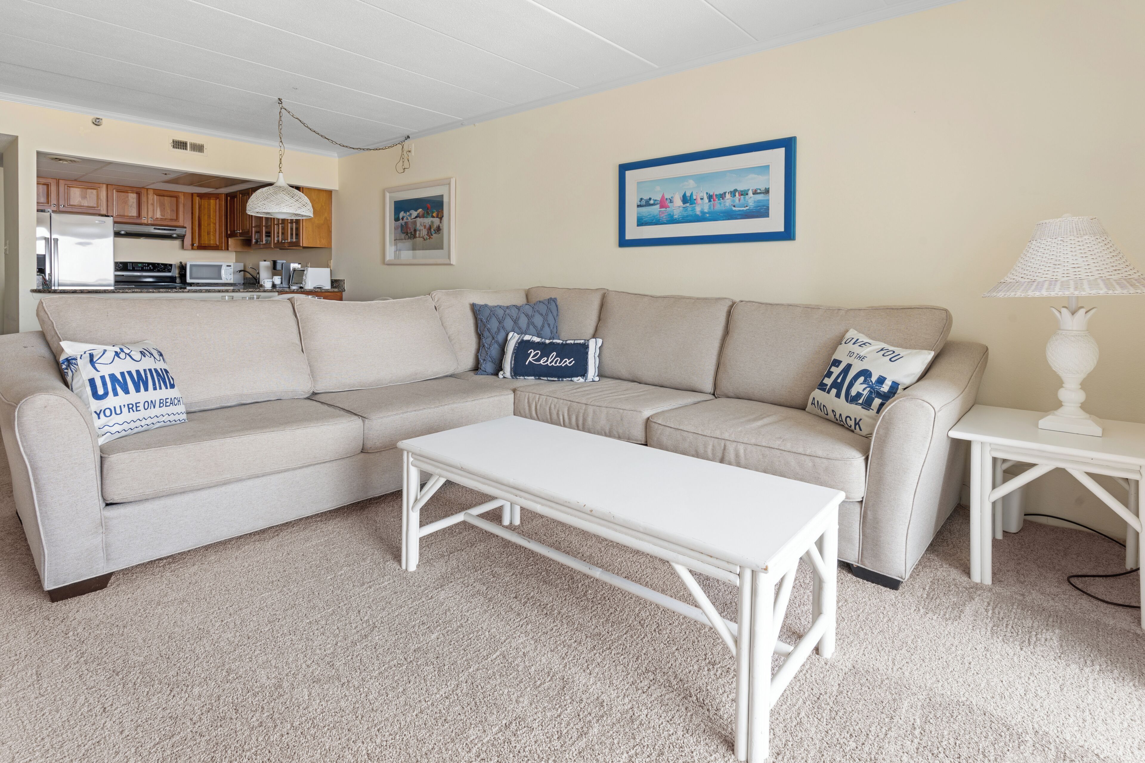 Ein Wohnzimmer mit einem Ecksofa, einem weißen Couchtisch und einer Lampe.