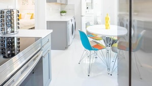 A modern kitchen with stainless steel appliances, a dining area with colorful chairs, and a laundry room. - Uhost AI 1B Retreat Fully Equipped w Patio (Fort Lauderdale)