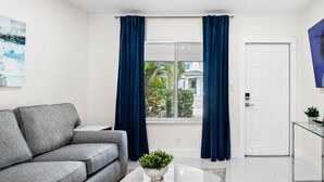 A modern living room with a grey sofa, a white coffee table, and a blue rug. - Uhost AI 1B Retreat Fully Equipped w Patio (Fort Lauderdale)
