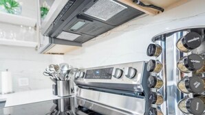 A kitchen with a stainless steel range hood, a built-in oven, and a spice rack with various spices. - Uhost AI 1B Retreat Fully Equipped w Patio (Fort Lauderdale)