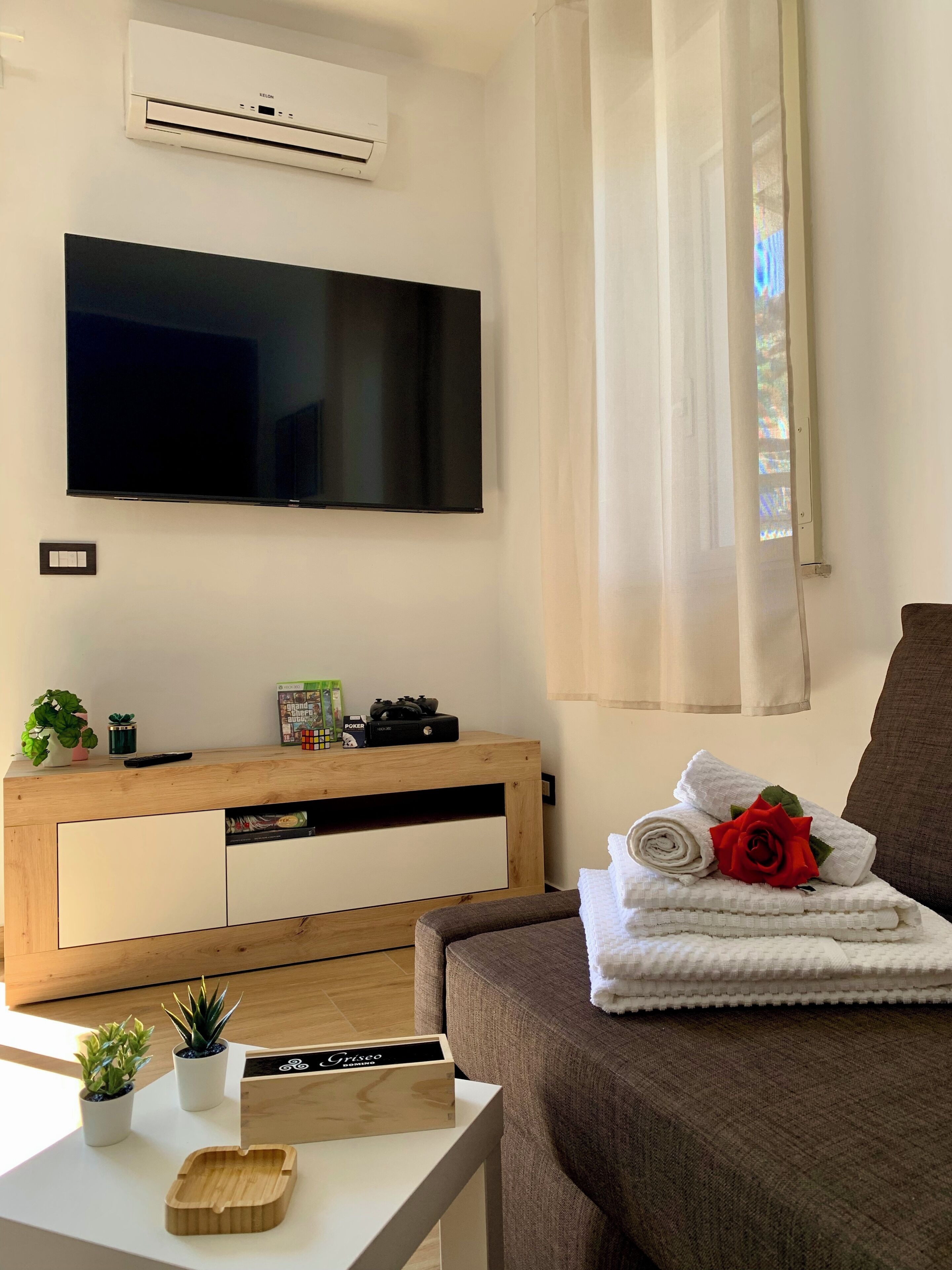 Un salon moderne doté d’un téléviseur à écran plat, d’un meuble de rangement en bois et d’un canapé confortable.