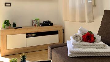 Un salon moderne doté d’un téléviseur à écran plat, d’un meuble de rangement en bois et d’un canapé confortable.