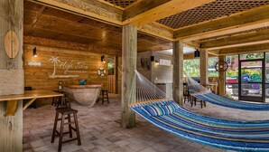 A wooden interior with a hammock, bar area, and a sign reading "High Tides Beach Bar." - Private Beach Access Steps Away,  Pool, Outdoor Bar, 2 Golf Carts, 360 Views. (Captiva)
