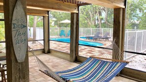 A hammock under a wooden pergola with a view of a pool and outdoor furniture. - Private Beach Access Steps Away,  Pool, Outdoor Bar, 2 Golf Carts, 360 Views. (Captiva)