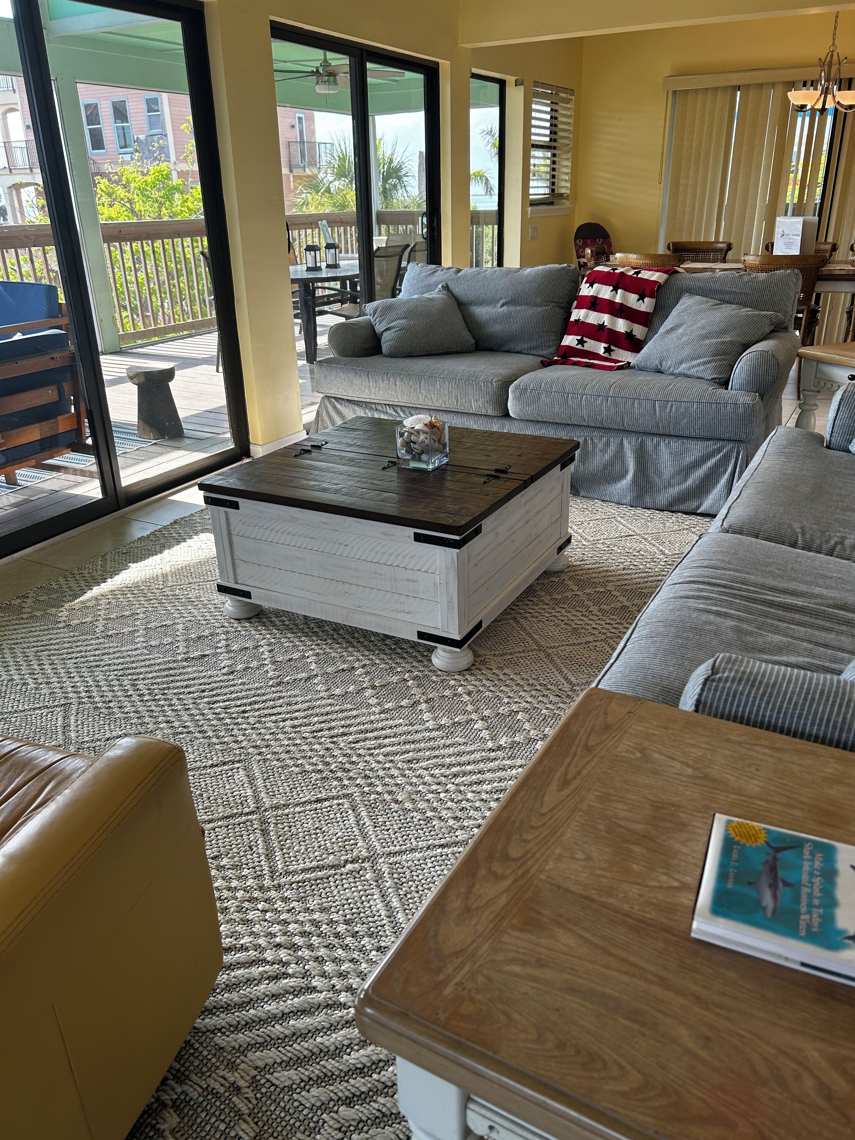 A living room with a large gray sectional sofa, a wooden coffee table, and a patterned rug.