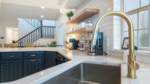 Een moderne keuken met een centraal eiland, zwarte kastjes en een gouden kraan.