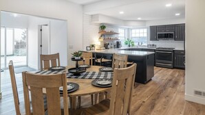 Een moderne keuken met een centraal eiland, houten stoelen en een eettafel gedekt voor zes personen.