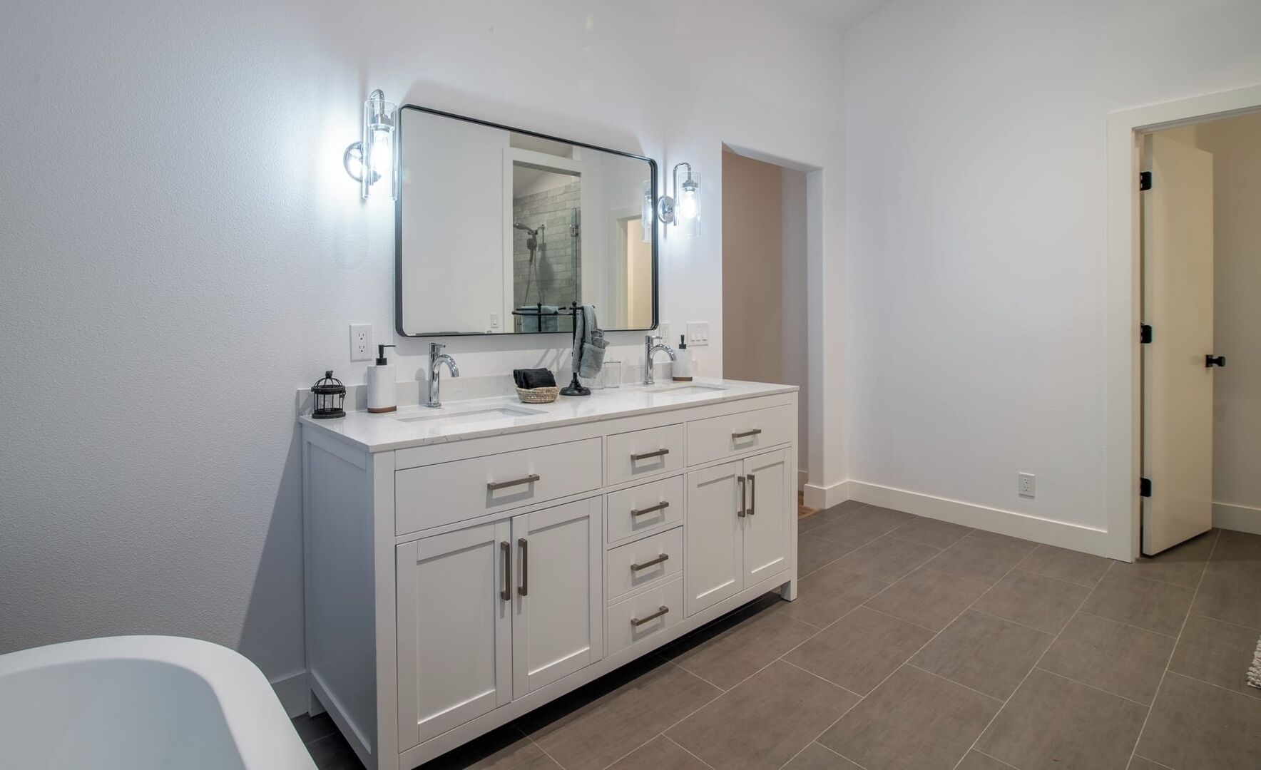 A bathroom with a white vanity, a mirror, and a shower.