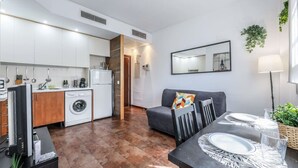 Une cuisine moderne avec des meubles blancs, un lave-linge et un coin repas avec une table mise pour deux personnes.