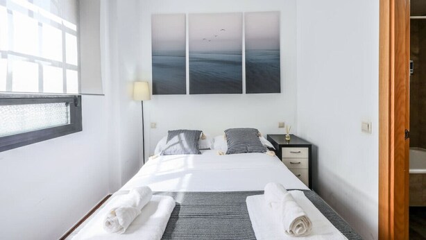 Une chambre d’hôtel avec un lit, une table de chevet, une lampe et un tableau représentant des oiseaux accroché au mur.