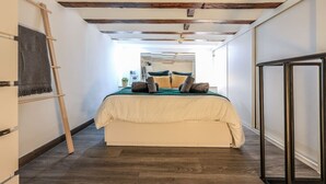 A bedroom with a bed, wooden beams, a ladder, and a wardrobe. - Cozy & Discreet apartment in Madrid (Madrid)