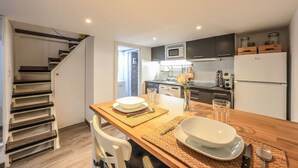 A modern kitchen with a dining area, featuring a wooden table set for two, a microwave, and a refrigerator. - Cozy & Discreet apartment in Madrid (Madrid)
