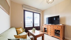 Een moderne woonkamer met een bank, een houten salontafel, een televisie en een kast.