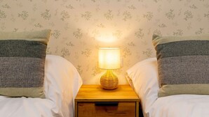 A bedroom with two beds, a nightstand with a lamp, and floral wallpaper. - Exclusive & Cozy Apartment in the Center of Soria (Soria)
