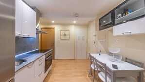 A modern kitchen with stainless steel appliances, a wooden door, and a dining area with a white table and chairs. - Exclusive & Cozy Apartment in the Center of Soria (Soria)