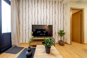 A living room with a TV, two potted plants, a yoga mat, and a wooden floor. - Exclusive & Cozy Apartment in the Center of Soria (Soria)
