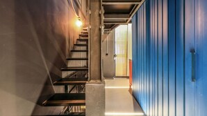 A staircase leading to a room with a blue door, a light fixture above the stairs, and a wall with a vertical panel design. - Design and Elegance in the Heart of Madrid (Madrid)