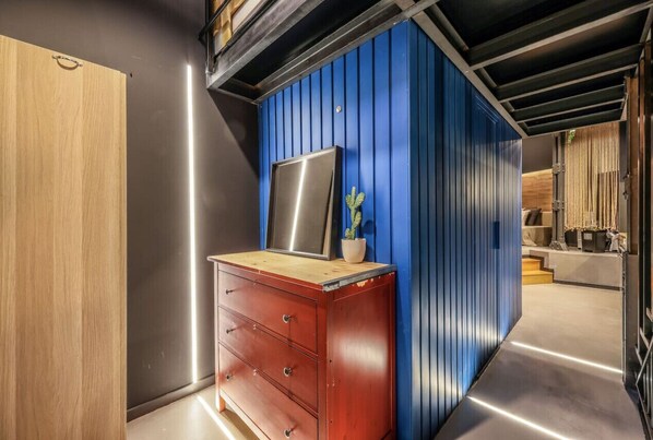 A modern interior with a wooden cabinet, a blue wall, and a stainless steel appliance.