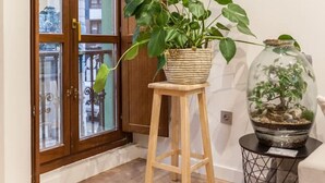 A wooden-framed door with glass panels, a potted plant on a stool, and a glass terrarium on a side table.