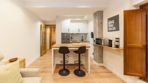 A modern kitchen with white cabinets, a wooden countertop, and two black bar stools.
