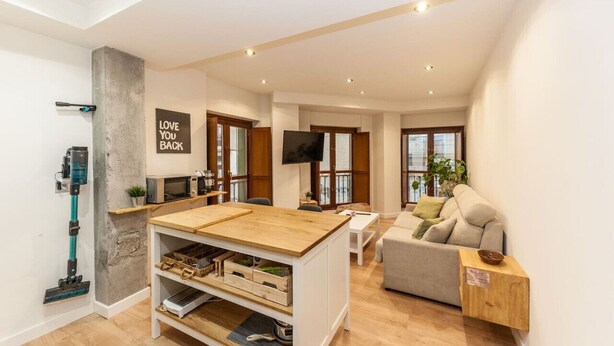 A modern living space with a kitchen area, a sofa, and a television.
