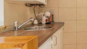 Una cocina con encimera de madera, un lavamanos, una lavadora y salpicadero de azulejos.