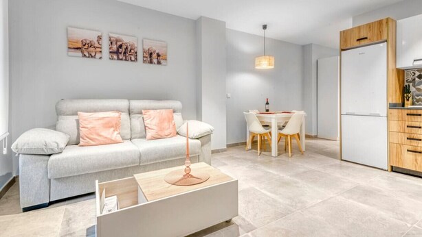 A modern living room with a sofa, a coffee table, and a dining area with a table and chairs.