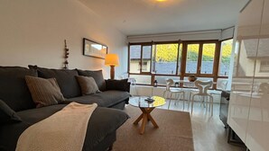 A modern living room with a sofa, a coffee table, and a dining area with chairs and a table. - Rural Apartment in the Mountains (Panticosa)