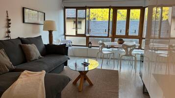 Un salon moderne avec un canapé, une table basse ronde et un coin repas comprenant des chaises et une table.