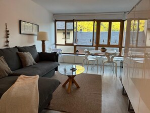 Un salon moderne avec un canapé, une table basse ronde et un coin repas comprenant des chaises et une table.