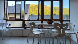 A room with large windows, a table with chairs, and a view of a mountain. - Rural Apartment in the Mountains (Panticosa)