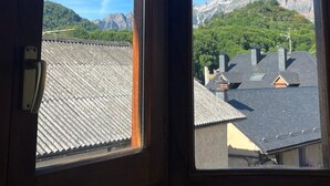 A window with a view of a mountain range and a residential area. - Rural Apartment in the Mountains (Panticosa)