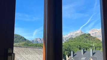 Una ventana con vistas a una cadena montañosa y una zona residencial.