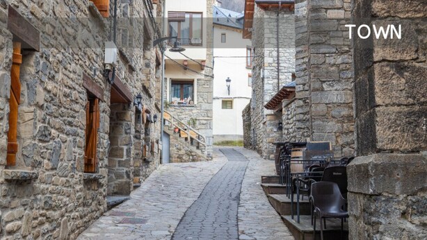 A narrow cobblestone street flanked by stone buildings with outdoor seating areas. - Rural Apartment in the Mountains (Panticosa)