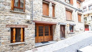 A stone building with a wooden door and windows, a sign that reads "Cerveceria," and a cobblestone street. - Rural Apartment in the Mountains (Panticosa)