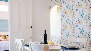 A dining table set with white chairs, a bottle of wine, and plates. - Andalusian Flavour in Heart of Seville 4´giralda (Sevilla)