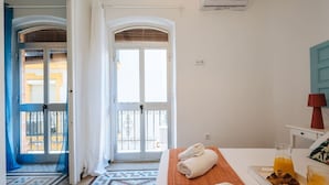 A hotel room with a bed, a bedside table with a lamp, a window with curtains, and a view of the outside balcony. - Andalusian Flavour in Heart of Seville 4´giralda (Sevilla)